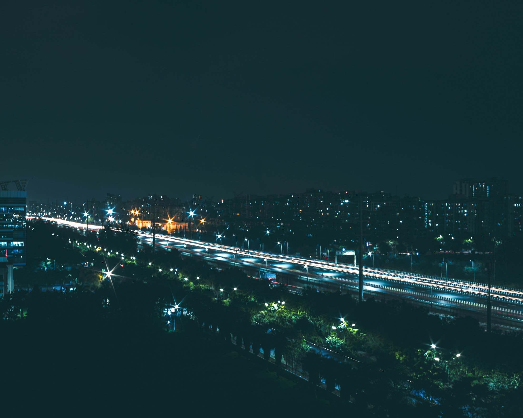 Night traffic on the expressway through Noida with residential blocks behind